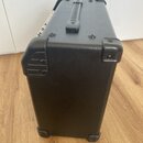 Černý kytarový kombozesilovač s povrchem z texturovaného vinylu. Horní strana je vybavena plastovou rukojetí a čtyři rohy jsou chráněny černými plast…