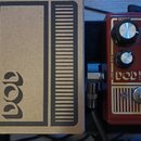Fotografie zachycuje tři efektové pedály vedle sebe. Uprostřed je červený pedál s nápisy DOD a MEATBOX SUBSYNTH, vybavený čtyřmi ovládacími knoflíky…