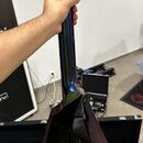 Detail zadní strany krku a těla elektrické kytary s přechodovým barevným lakem v odstínech modré, fialové a zelené. Na těle je připevněn černý popruh…
