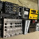 Černý přepravní kufr s osazenými kytarovými efekty a procesory. V horní části jsou zařízení SIMPLIFIERX, BOSS Noise Suppressor NS-2 a žlutý pedál NUX…