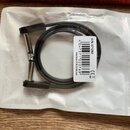 Černý kabel s kovovými konektory, sbalený do kroužku a umístěný v průhledném plastovém obalu. Na bílém štítku je uveden kód L0473711020769, označení…