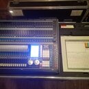 Světelný kontrolér v transportním kufru. Na zařízení je nápis LIGHT CONTROLLER a logo Avolites s označením TITAN. Ovládací panel obsahuje velké množs…