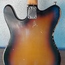 Zadní strana elektrické kytary s tónem sunburst (přechod od černé k žluté). Na krku je vidět nápis 0121. Povrch těla vykazuje výrazné opotřebení, zej…