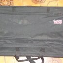 Černý obal na hudební nástroj s úložnou kapsou v horní části. Na kapse je umístěno červenobílé logo s nápisem GATOR Cases. Povrch materiálu vykazuje…