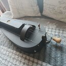 Černý kolový lyra nebo hurdy-gurdy s dřevěnou klikou. Nástroj má matný černý povrch a čtyři viditelné struny. Na těle nejsou žádné viditelné značky a…