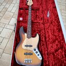 Elektrická basová kytara s korpusem v barevném přechodu od žluté přes hnědou k černé a světle hnědým hmatníkem. Nástroj má béžový pickguard a čtyři o…