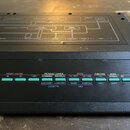 Detailní pohled na ovládací panel černého elektronického zařízení. Na horní části je šedý panel s nápisy TX7, DX DATA ENTRY a DX FUNCTION. Spodní čás…