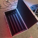 Otevřený hliníkový přepravní kufr s vnitřním polstrováním. Víko je vyloženo černou akustickou pěnou s pyramidovým profilem, spodní část obsahuje čern…