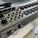 Detailní pohled na zadní panel šedého digitálního mixážního pultu značky ALLEN&HEATH. Jsou vidět různé konektory, včetně dvou XLR výstupů s nápisem M…