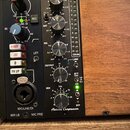 Detailní pohled na dva moduly studiového vybavení v dřevěném rámu. Levý modul nese značku Neve a popisy I/P GAIN, LINE DI, LIFT, +48V, FR I/P a MIC P…