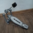 Šedý pedál pro elektronické bubny s černým beaterem. Na stupni je uveden nápis ALESIS a v pravé části jsou čtyři svislé čárky. Konstrukce je kovová,…