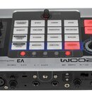 Stříbrno-černý vokalní procesor s nápisem ZOOM V3 Vocal Processor. Zařízení obsahuje mřížku bílých a červených tlačítek s popisky jako EFFECT OFF, EN…