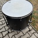 Černý buben s bílým membránou, umístěný na zemi na dlažbě. Na horní části membrány je logo s nápisem "REMO". V dolní části korpusu se nachází obdélní…