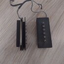 Na dřevěném povrchu leží dvě části černé sňímače k elektrické kytáře. Levá část je zobrazená z boku a je k ní připojen šedý kabel. Pravá část je obdé…