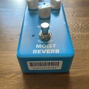 Modrý kytarový efekt s nápisem MOIST REVERB a TRUE BYPASS. Na horní straně jsou tři bílé oválné ovladače s popisky DECAY, TONE a MIX, doprovázené stř…