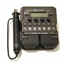 Šedý multifunkční procesor s nápisem A1 FOUR ZOOM Multi-Effects Processor. Zařízení obsahuje displej, ovládací knoflíky a pět stoupacích spínačů s čí…