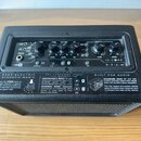 Černý kombozesilovač s texturovaným povrchem a ovládacím panelem z horní strany. Na panelu jsou nápisy BLACK STAR, ID:CORE BEAM a ovládací prvky jako…