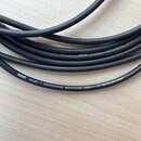 Černý mikrofonní kabel smatným povrchem, který je složen do několika smyček. Na izolaci je bílý nápis KLOTZ MY206 - PROFESSIONAL MICROPHONE CABLE - B…