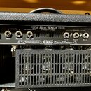Zadní panel kytarového zesilovače značky Mesa/Boogie. Na černém povrchu jsou nápisy FILLMORE 100 VACUUM TUBE AMPLIFIER, (USE SHIELDED CABLE), DYNA-WA…