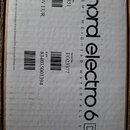 Fotografie znázorňuje kartónový obal od hudebního nástroje. Na krabici je černý nápis nord electro 6 D a text SEMI WEIGHTED WATERFALL 61. Jsou zde uv…