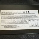 Detailní záběr na černý plastový štítek s bílým textem v angličtině. Štítek obsahuje sekce "Special instructions to use batteries", "CHARGE" a varová…