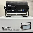 Černý LED reflektor s držákem, umístěný na bílém kartonu. Na přístroji i na krabici je nápis cameo colours of light THUNDERWASH 600 RGBW. Zařízení má…