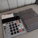 Šedý sampler s černým displejem a ovládacími prvky. Na horní části je nápis K.O.II, pod ním japonské znaky サンプラー a dále text 64 MB SAMPLER COMPOSER.…