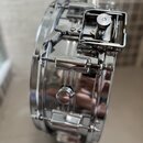 Detailní pohled na chromovaný obruč a mechanismus malého bubnu. Na kovovém těle jsou vidět ladicí šrouby a mechanismus napnutí s kovovými součástmi.…