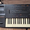 Černý digitální klavír s nápisem Roland G-800 ARRANGER WORKSTATION 64-VOICE POLYPHONY. Horní panel obsahuje řadu tlačítek a ovládacích prvků rozdělen…