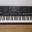 Černý digitální klavír s bílými a černými klávesami. Na horním panelu je nápis YAMAHA, displej a řada ovládacích tlačítek s popisky. V pravé části pa…