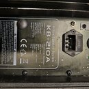 Fotografie zachycuje zadní panel černého aktivního reproduktoru. Je zde viditelný štítek s nápisy Active Speaken-System KB-210A, technické specifikac…