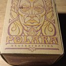 Kartonová krabice s hnědým povrchem a fialovým potiskem. Na horní straně je stylizovaná tvář postavy a nápisy POLARA a REVERBERATION. Rohy krabice vy…