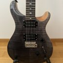 Elektrická kytara s tmavě šedým plamenovitým topem a hnědými dřevěnými boky. Je vybavena dvěma černými humbuckery, dvěma ovládacími knoflíky a přepín…