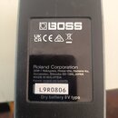 Zadní strana černého efekt pedálu s textem a logy. Je zde vidět logo BOSS, značení UK CA, CE a symbol přeškrtnuté popelnice. Dole je uveden nápis Rol…