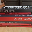 Černý klávesový kontrolér s nápisem AKAI PROFESSIONAL MPC KEY 61. Přístroj má červený spodní panel s řadou konektorů a ovládacích prvků. Pod nástroje…