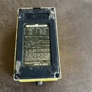 Fotografie zachycuje zadní stranu efekt pedálu v žluté barvě. Na černé kovovédesce je uveden nápis BOSS AC ADAPTOR a tabulka s napájecími adaptéry AC…