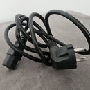 Černý napájecí kabel s evropskou síťovou vidlicí a konektorem na druhém konci. Kabel je svinutý do klubíčka a položený na šedém povrchu. Na izolaci k…