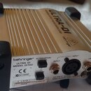 Stříbrná DI box s černými gumovými nohami. Na horní části je nápis ULTRA-DI a logo behringer, na zadním panelu jsou nápisy behringer, ULTRA-DI MODEL…