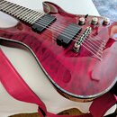 Elektrokytara s červeným vyznačením dřeva a lesklým povrchem. Nástroj má dva černé humbuckery, tři kovové oválné knofíky a stříbrný most. Přivázaný j…