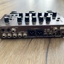 Zadní strana kytarového procesoru v hnědé barvě. Na zadním panelu jsou vidět konektory s popisky INPUT SENS (1-GUITAR IN, 2-GUITAR IN), SEND, RETURN,…