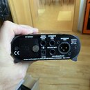 Detailní pohled na zadní panel černého elektronického zařízení. Jsou zde vidět konektory a nápisy: 9V BATTERY, STEREO MONITOR INPUT, INSTRUMENT /LINE…