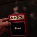 Malý červený kytarový kombo zesilovač s černým předzesílovačem. Na horním ovládacím panelu jsou nápisy GUITAR AMPLIFIER, INPUT, VOLUME, TONE, POWER F…