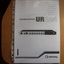 Fotografie znázorňuje bílý printed manuál k USB audio rozhraní. Na obálce je uveden nápis USB AUDIO INTERFACE UR 824 a v pravém dolním rohu logo s te…