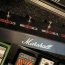 Černý kytarový spínací pedalboard značky Marshall. Na horní hraně jsou umístěny kovové spínače s červenými popisky: CLEAN, CRUNCH, CRUNCH, 1, 2, MAST…