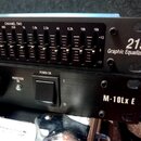 Dva černé rackové přístroje naskládané na sebe. Horní zařízení je grafický ekvalizér s nápisem 215 Graphic Equalizer a označením CHANNEL TWO nad posu…