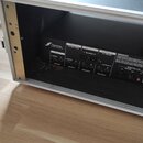 Zadní panel černého elektronického zařízení umístěného v transportním kufru. Na zařízení je viditelné logo a nápis FRACTAL AUDIO SYSTEMS a označení v…