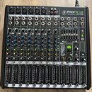Černý 12kanálový mixážní pult s nápisem ProFX12v2 PROFESSIONAL EFFECTS MIXER. Zařízení obsahuje řadu vstupů, potenciometrů a posuvníků s bílými popis…