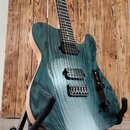 Elektrická kytara s modrozeleným průsvitným povrchem, pod kterým je vidět výrazná struktura dřeva. Nástroj má dva černé humbuckery, jeden ovládací kn…
