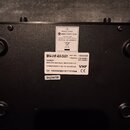 Fotografie zachycuje zadní stranu černého elektronického zařízení. Na povrchu jsou dvě bílé nálepky; horní nese logo a text MALONE electronic star, d…