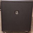 Zadní strana černého basového komba v texturovaném potahu s kolečky. Uprostřed je ovládací panel s nápisem "Ampeg" a "SVT-4PRO". Povrch vykazuje mírn…